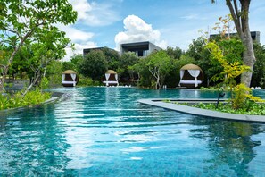 A swimming pool with a modern building in the background, surrounded by lush greenery. - Hilton Yala Resort (Thissamaharama)