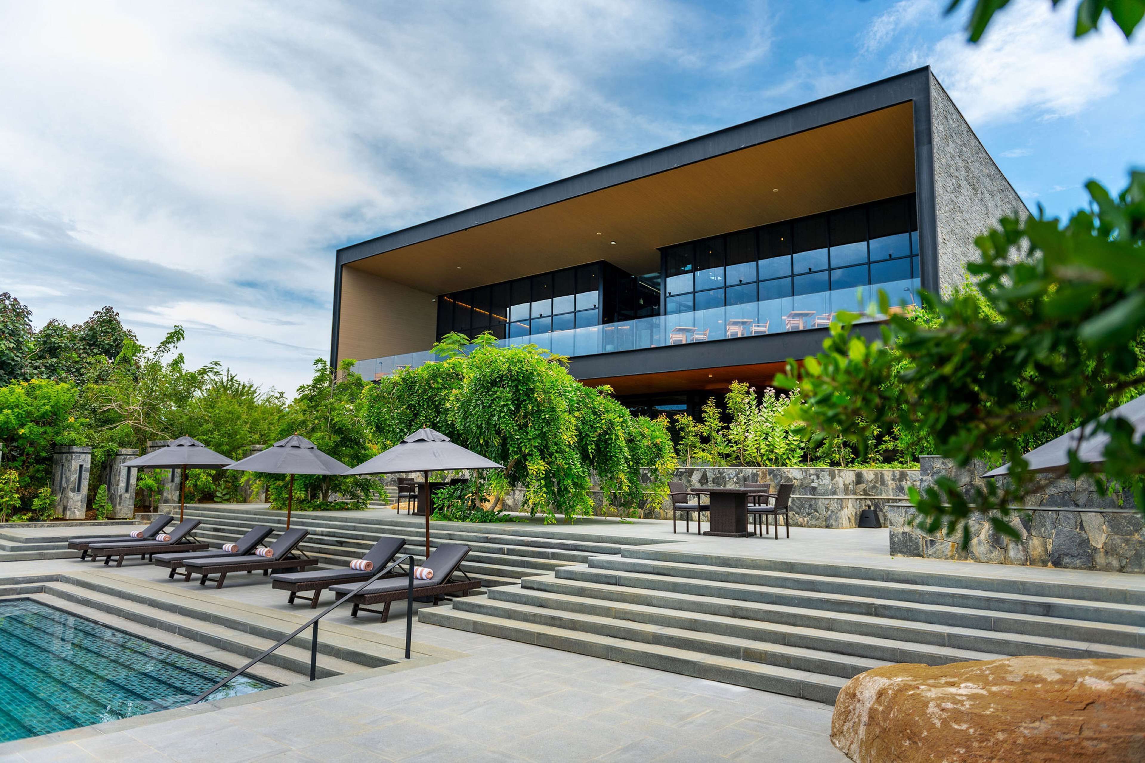 A modern building with a pool area, including lounge chairs and umbrellas.