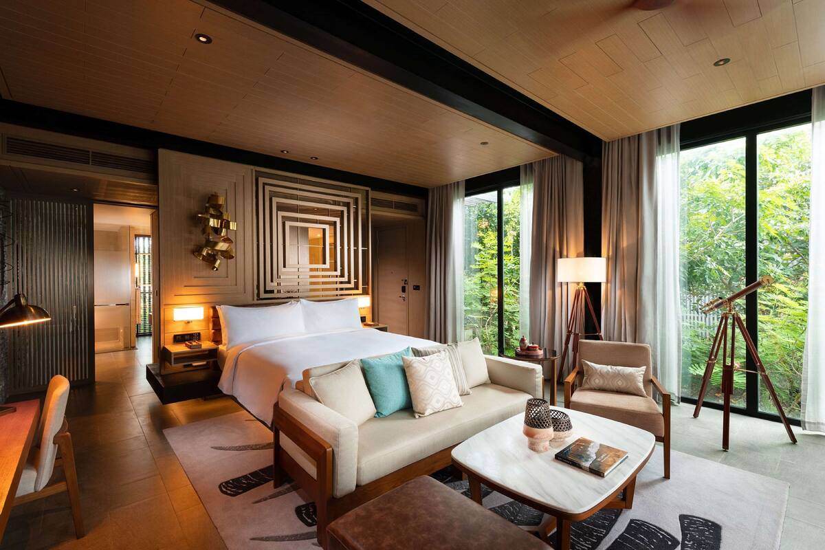 A hotel room with a large bed, a sofa, a coffee table, a desk, and a telescope.