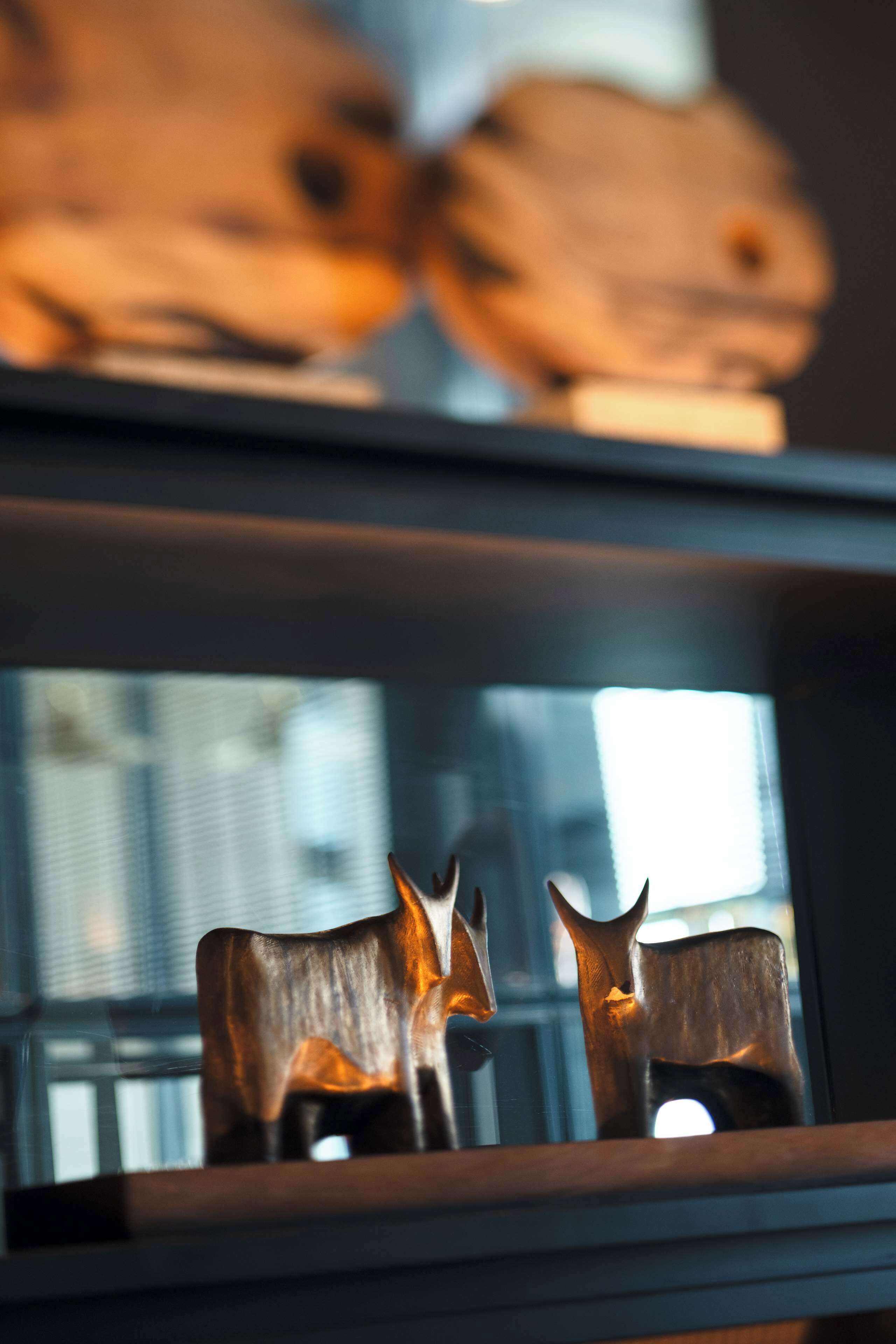 A wooden sculpture of a deer on a shelf.