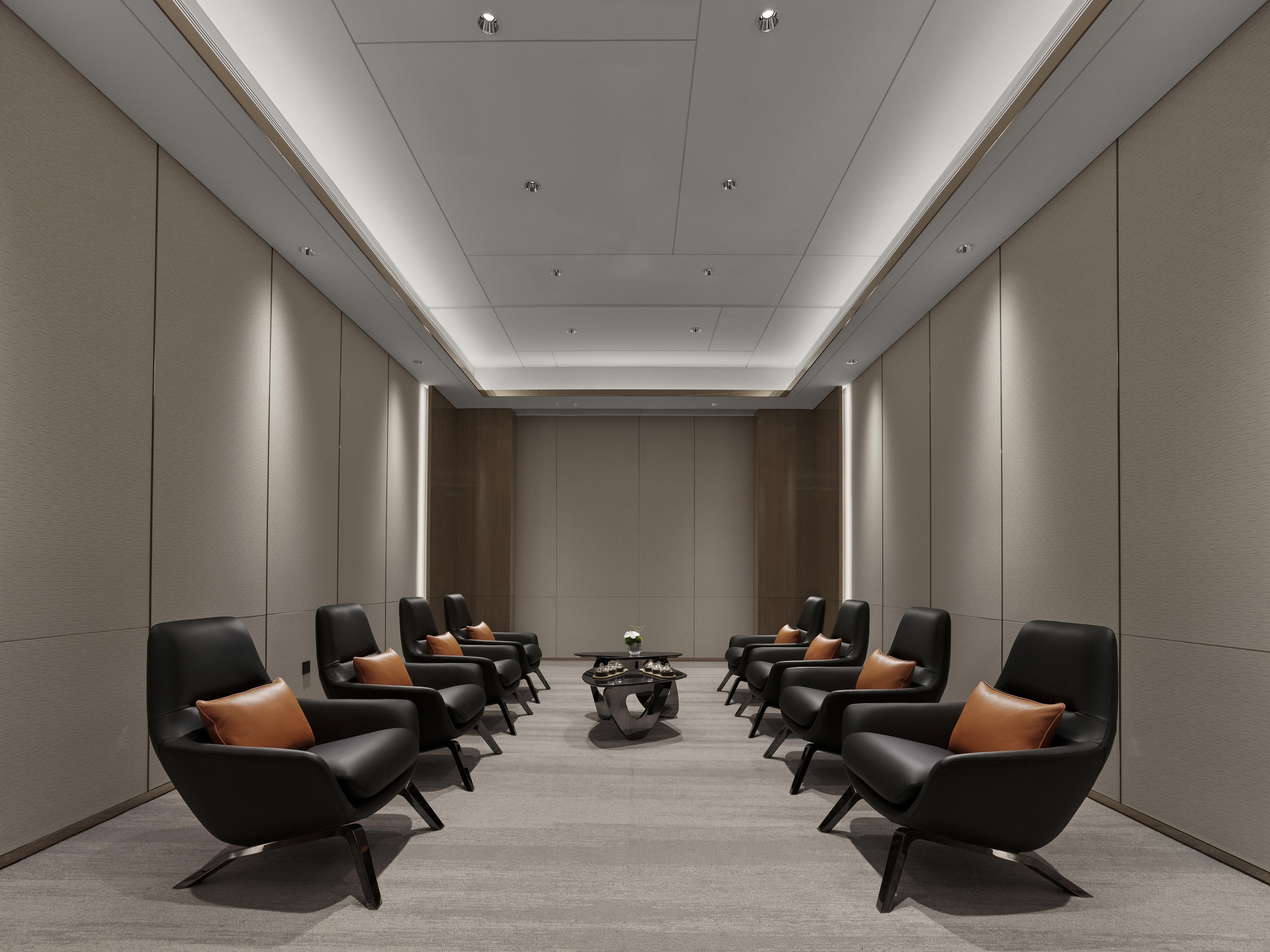 Un salón de conferencias con una larga mesa, sillas negras con cojines marrones y una mesa de centro.