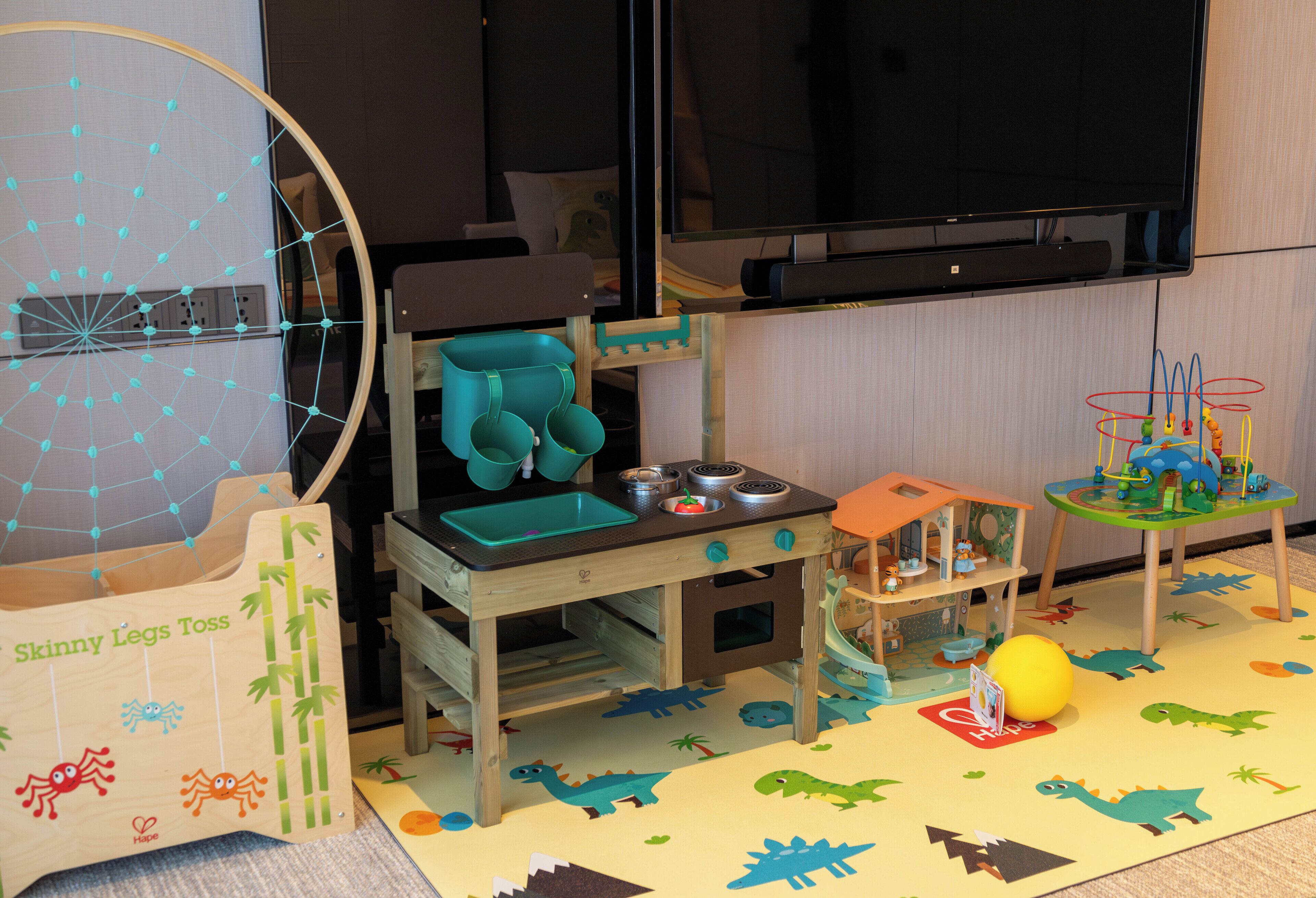 Uma área de recreação infantil com cozinha de brinquedo, um trem de brinquedo e uma bola.