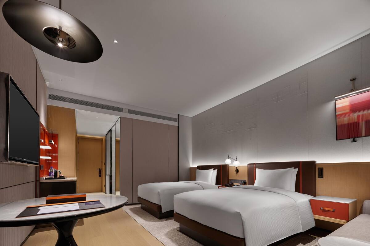 A modern hotel room with a large bed, bedside tables, a desk, and a TV.