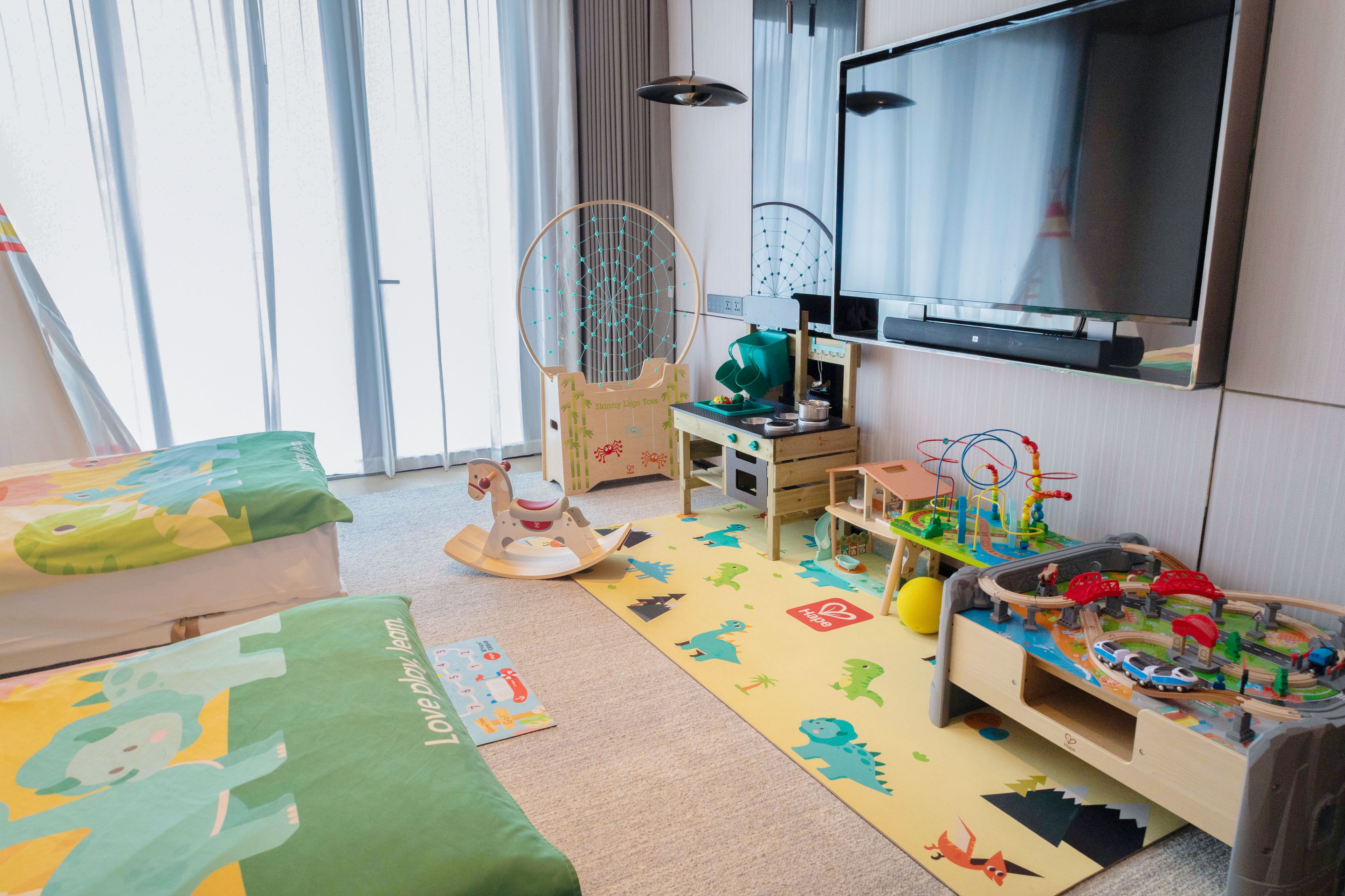 A child's playroom with a television, toys, and a rocking horse.