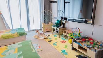 A child's playroom with a television, toys, and a rocking horse.