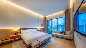 A modern hotel room with a large bed, bedside tables, a sofa, and a city view. - Doubletree By Hilton Cangnan (Wenzhou)