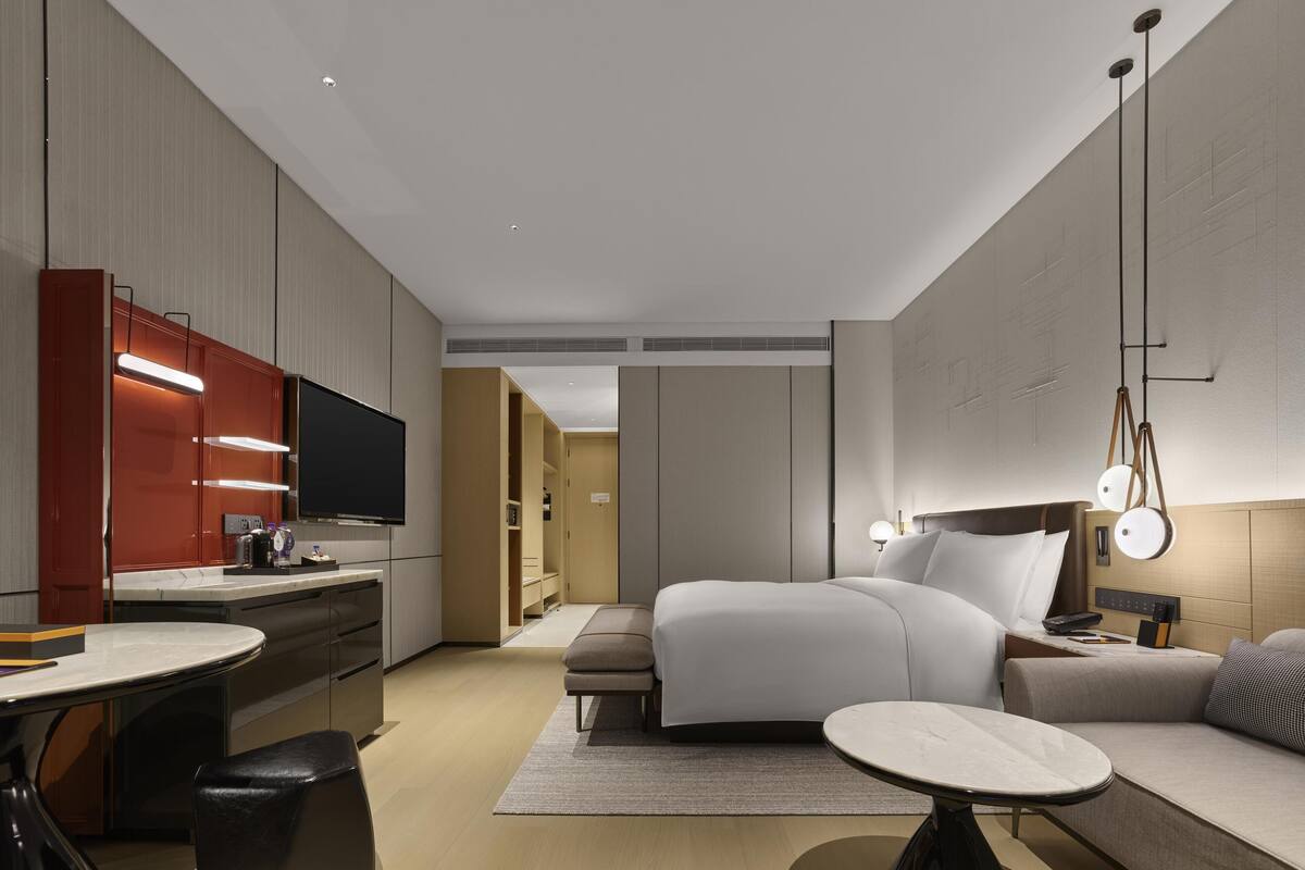 A modern hotel room with a bed, bedside table, and a TV.