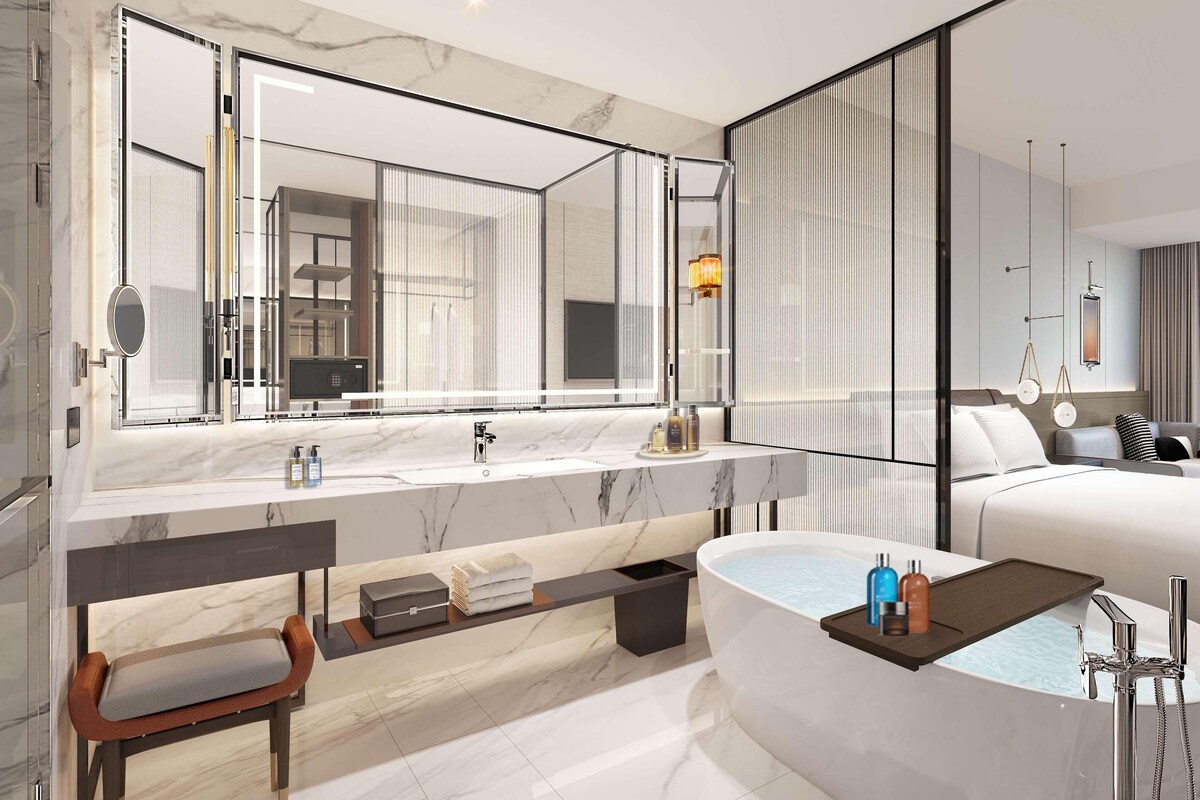 A modern bathroom with a large mirror, a bathtub, and a vanity with a sink.