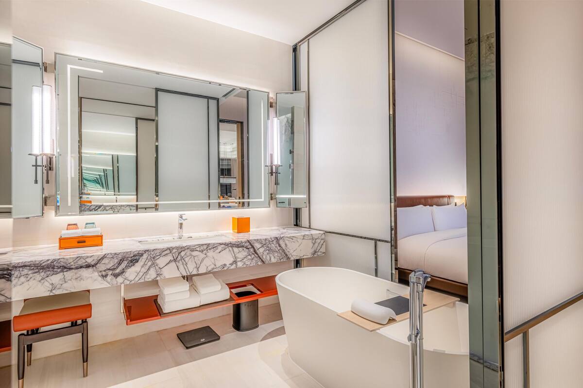 A modern bathroom with a marble sink, a large mirror, a bathtub, and a separate shower area.