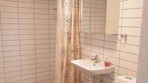 Ein Badezimmer mit Dusche, Toilette, Waschbecken und Spiegel.