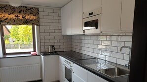 Eine Küche mit weißen Schränken, einer schwarzen Arbeitsplatte, einem Fenster mit Aussicht und einem eingebauten Backofen.