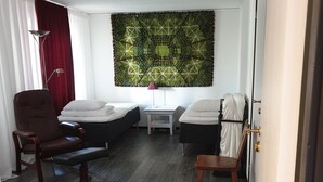 Ein Zimmer mit zwei Betten, einem Schreibtisch, einem Stuhl und einem großen Wandteppich.