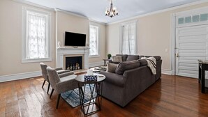 Ein Wohnzimmer mit Kamin, Fernseher, Sofa und Couchtisch.