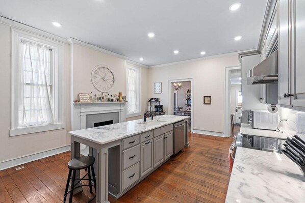 A spacious kitchen with a large island, wooden flooring, and modern appliances.