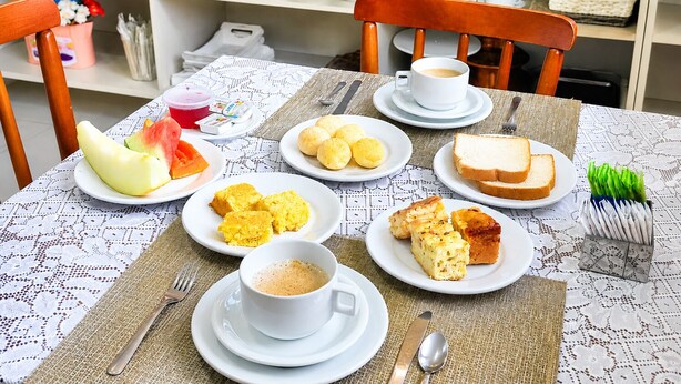 Une table mise pour le petit-déjeuner, avec des assiettes remplies de nourriture, une tasse de café et un set de table.