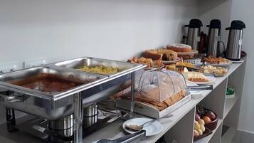 A buffet setup with various food items and serving utensils.