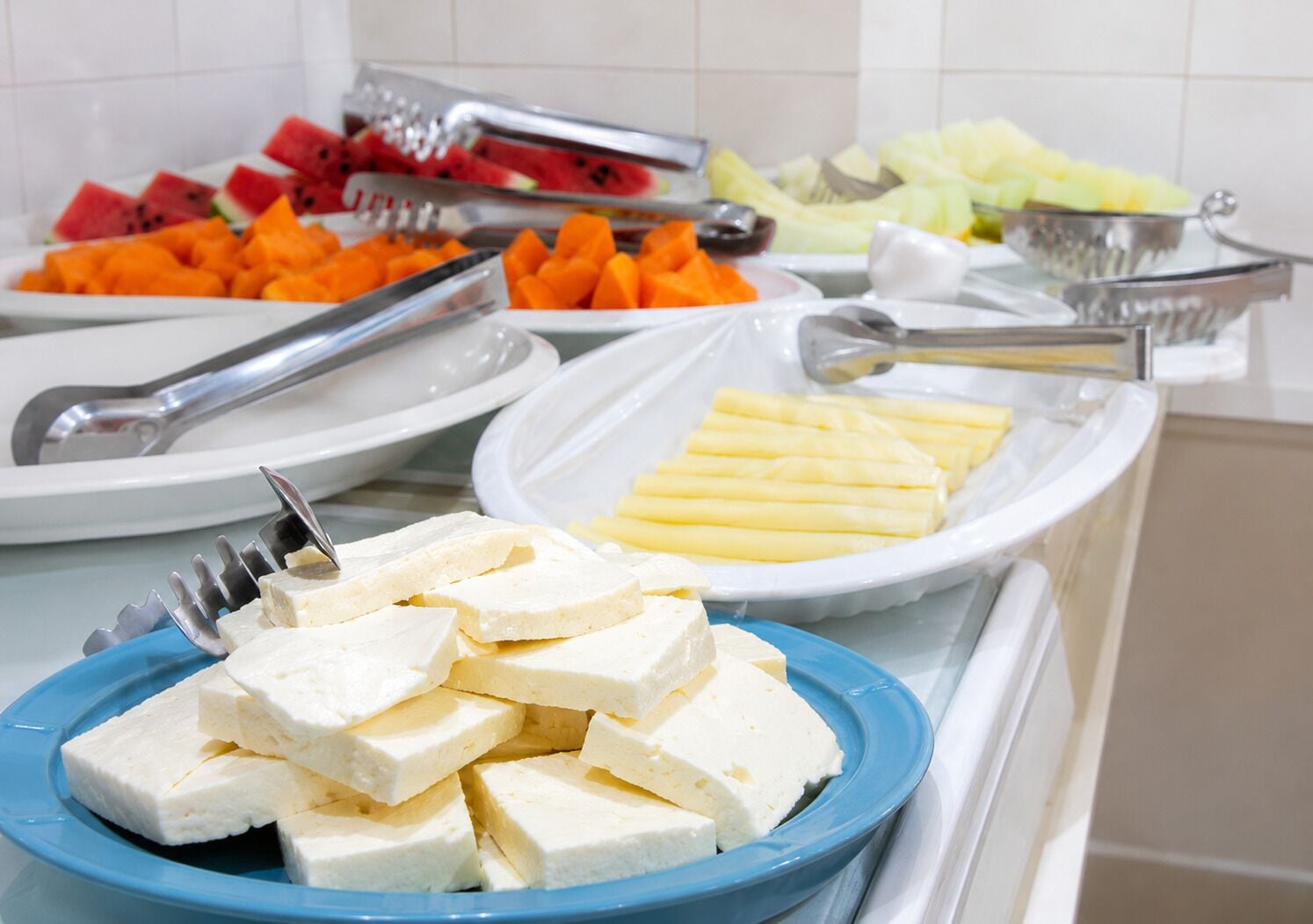 Buffet com diversos alimentos, incluindo melancia, cenouras e queijo.