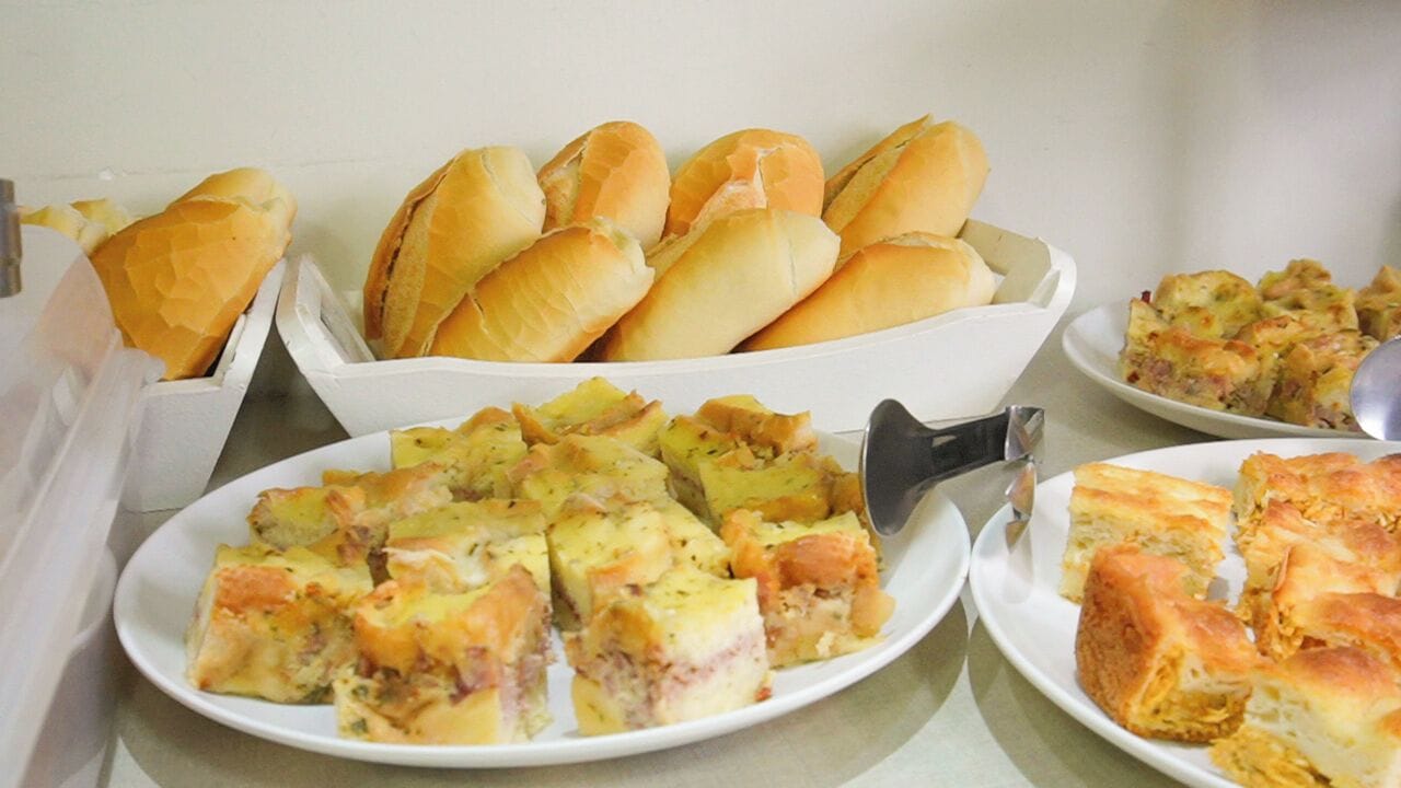 A buffet with various dishes including bread rolls, quiche, and a salad.
