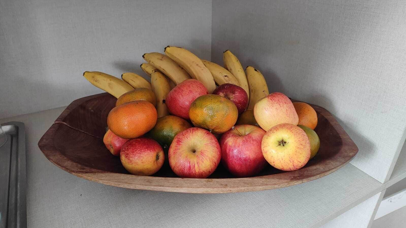 Eine Holtschale, gefüllt mit verschiedenen Früchten, darunter Äpfel, Orangen und Bananen.