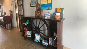 Un comptoir d’accueil avec une roue en bois, des œuvres d’art encadrées et des brochures d’information.