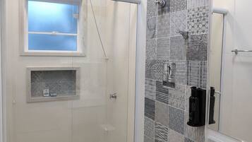 Uma casa de banho moderna com cabine de duche em vidro, lavatório e azulejos estampados nas paredes.