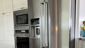 Een keuken met roestvrijstalen afwerking, inclusief een ingebouwde oven, magnetron en waterdispenser.