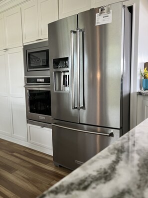 Una cocina de acero inoxidable con horno integrado, microondas y dispensador de agua.