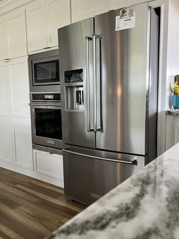 Una cocina de acero inoxidable con horno integrado, microondas y dispensador de agua.