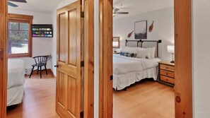 Une chambre à coucher avec un lit, des tables de chevet, une chaise, un téléviseur et une fenêtre.