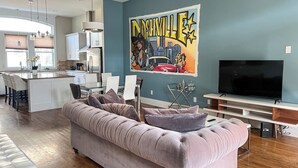 En moderne stue med en stor sofa, et fladskærms-tv og et bybillede malet på væggen.