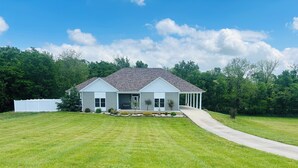 A single-story house with a covered porch, a front yard with a lawn, and a driveway leading to the entrance. - Bourbon Trail POOL Zone! HotTub! PoolTable! PingPong! GoldenTee! BigYard! PETS! (Springfield)
