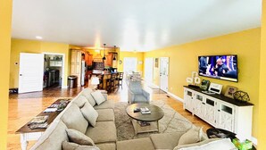 A spacious living room with a large sofa, a coffee table, and a television mounted on the wall. - Bourbon Trail POOL Zone! HotTub! PoolTable! PingPong! GoldenTee! BigYard! PETS! (Springfield)