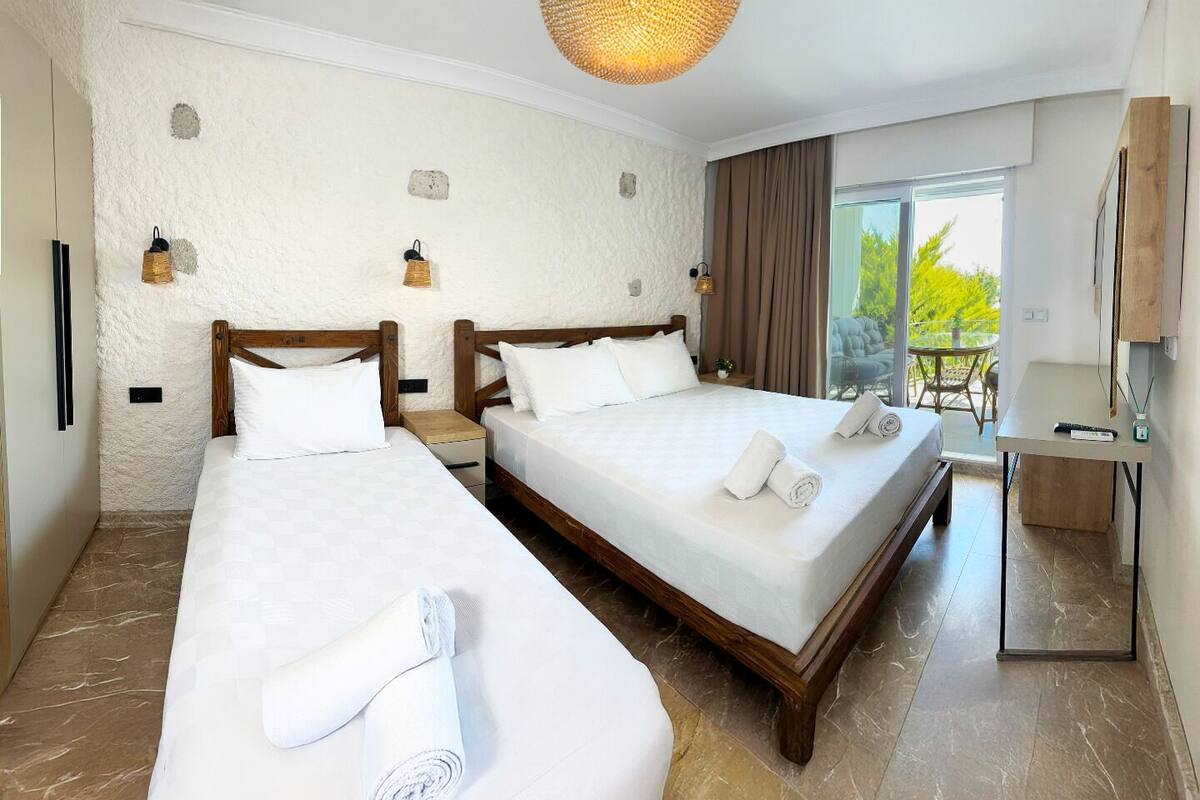 A hotel room with two beds, a balcony, and a desk with a chair.