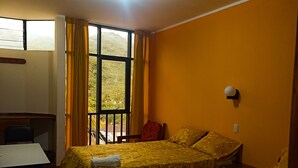 A room with two beds, a desk, and a window with curtains. - Hotel Payanito (Chanchamayo)