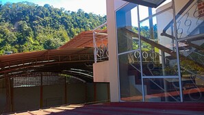 A modern building with a glass facade, a metal staircase, and a red roof. - Hotel Payanito (Chanchamayo)