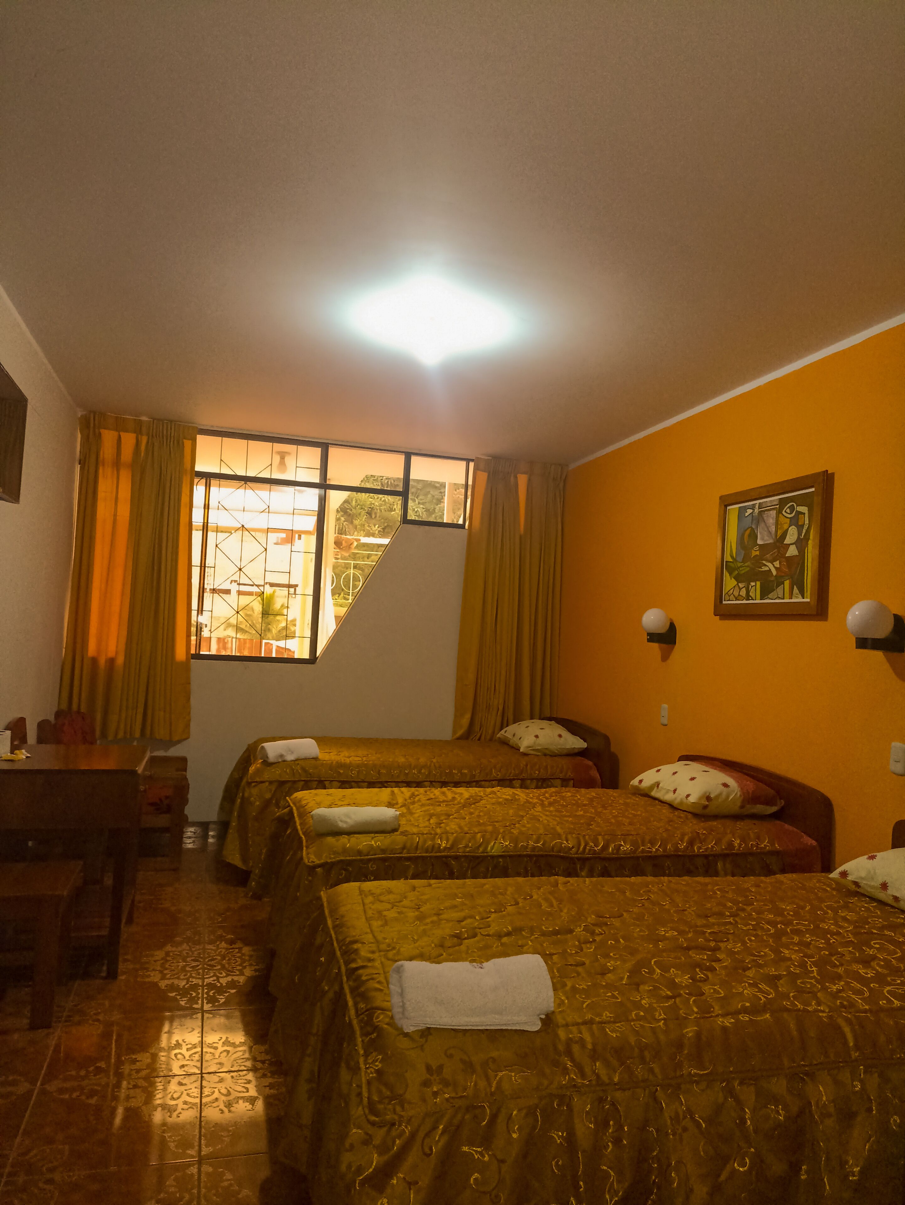A hotel room with two beds, a dining table, and a window with curtains.