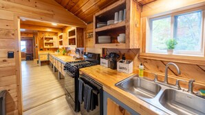 Eine Holzhütte mit einer Küche, inklusive Herd, Spüle und Holzschränken.