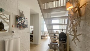 A spacious room with a high ceiling, a staircase, and a view of the outdoors. - Les Pieds dans l'Eau, bay view for 6 people (Le Crotoy)