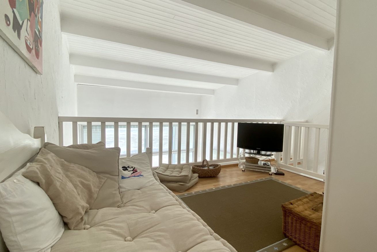 Een woonkamer met een bank, een televisie, een raam met uitzicht en een balkon.