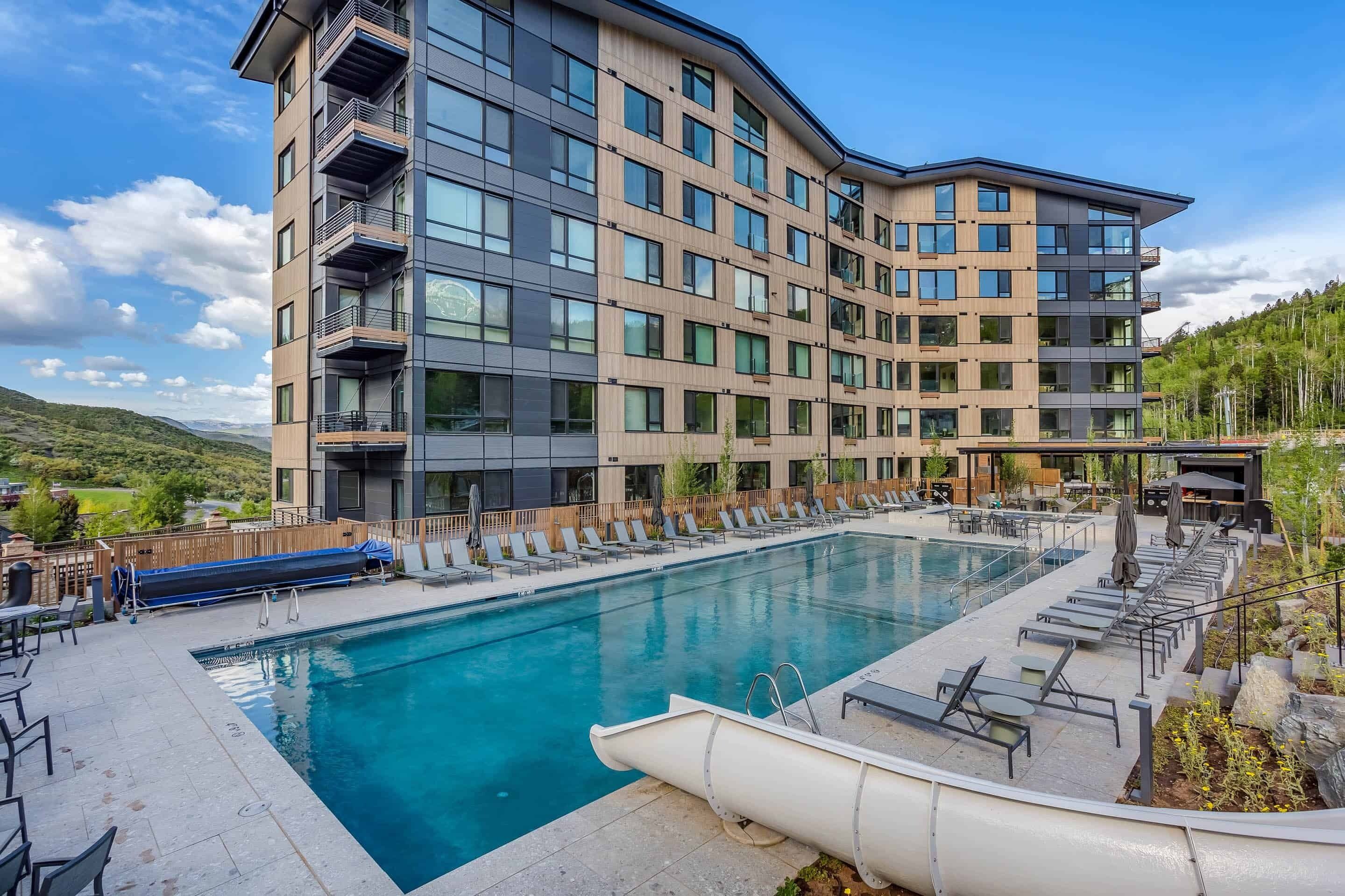 Un hotel moderno con piscina, mobiliario exterior y vistas del paisaje circundante.