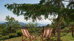 Two striped lounge chairs under a wooden pergola with a view of mountains.