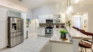 Una cucina moderna con elettrodomestici in acciaio inossidabile, un'isola in marmo e illuminazione a sospensione.