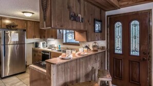 Una cocina con armarios de madera, un refrigerador de acero inoxidable, un microondas y una cafetera.
