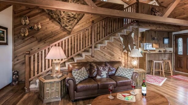 Un interior de madera acogedor con un sofá de cuero, una escalera y un comedor.