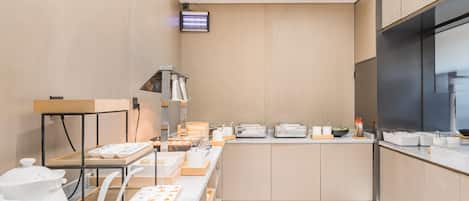 A modern kitchen with wooden cabinets, a large island with food items, and a flat-screen TV mounted on the wall.