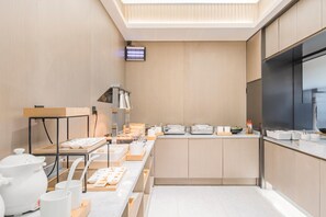 Une cuisine moderne avec des meubles en bois, un grand îlot central où sont disposés des aliments et un téléviseur à écran plat fixé au mur.