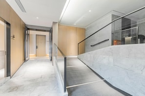 A modern interior with a marble staircase, glass railings, and wooden paneling. - Ji Hotel (Shanghai)