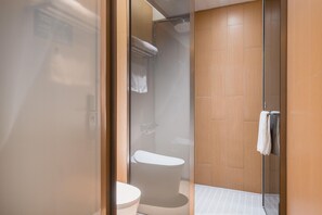 Une salle de bain moderne avec une douche à parois de verre, des toilettes et un meuble-lavabo en bois.