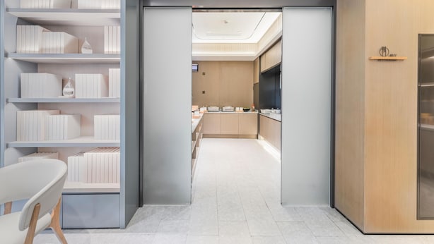 Un intérieur moderne avec un couloir central menant à un espace cuisine, comprenant une bibliothèque et un coin repas.