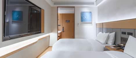 A hotel room with two beds, a large window, a flat-screen TV, and a bedside table with a phone and tissues.